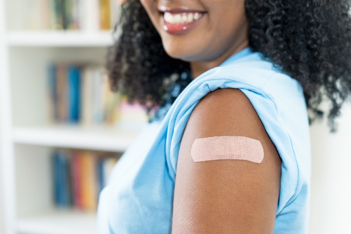 Close up - plaster on arm of latin american woman after third vaccination against Covid 19 for protection against omicron variant