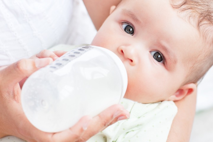 Close-up of a baby drinking milk in his mother's arms