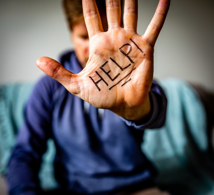 Man holds hand to camera with HELP written on palm.