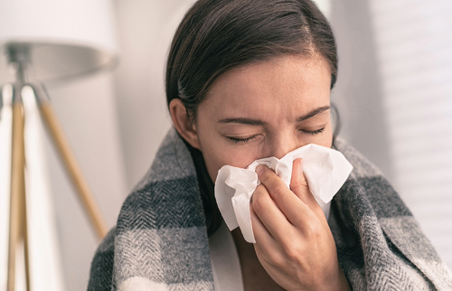 Woman sneezing into tissue