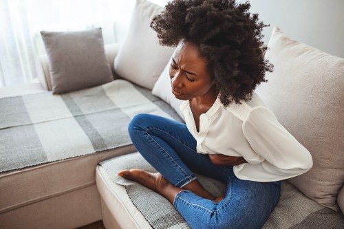 Cropped shot of an attractive young woman lying on her sofa alone and suffering from period cramps at home. Ouch! My tummy!