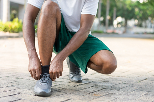 Person kneeling down to fix shoe