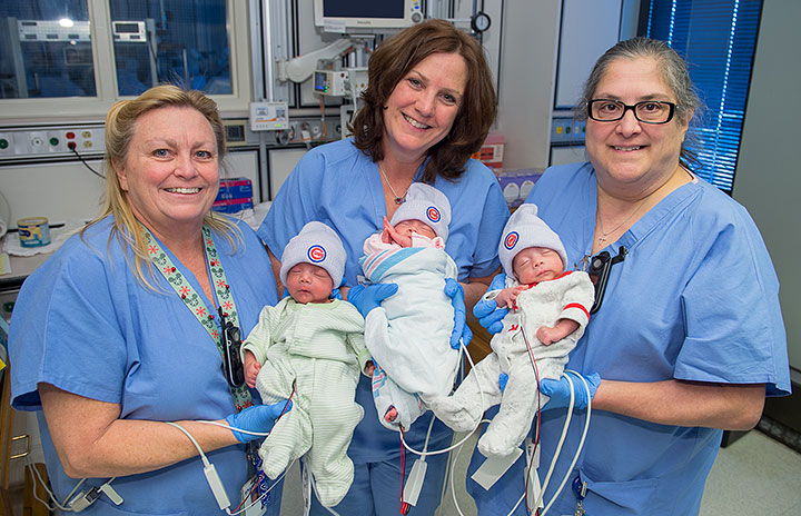 ISCU nurses triplets who are donning their new Cubs knit caps.